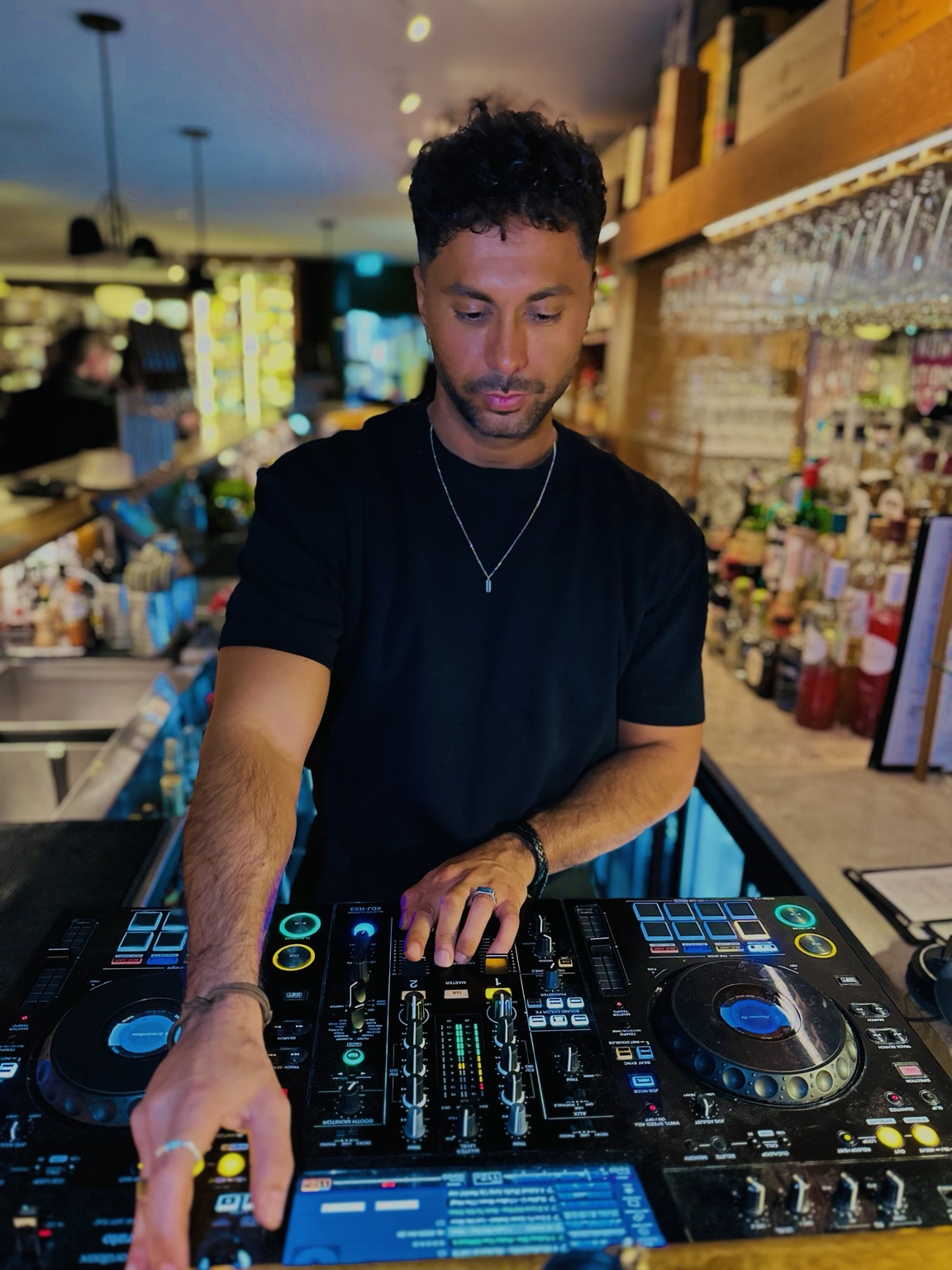 Merano spelar ett DJ-set i en bar med blått ljus